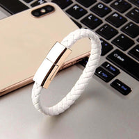 Charging cable bracelet shown on a keyboard, featuring a sleek white woven design and stylish clasp.