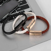 Charging cable bracelet in black, white, and brown colors placed on a laptop.